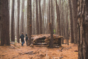 two-kids-building-a-fort-in-the-woods-on-a-rainy-d-2021-04-20-17-24-34-utc
